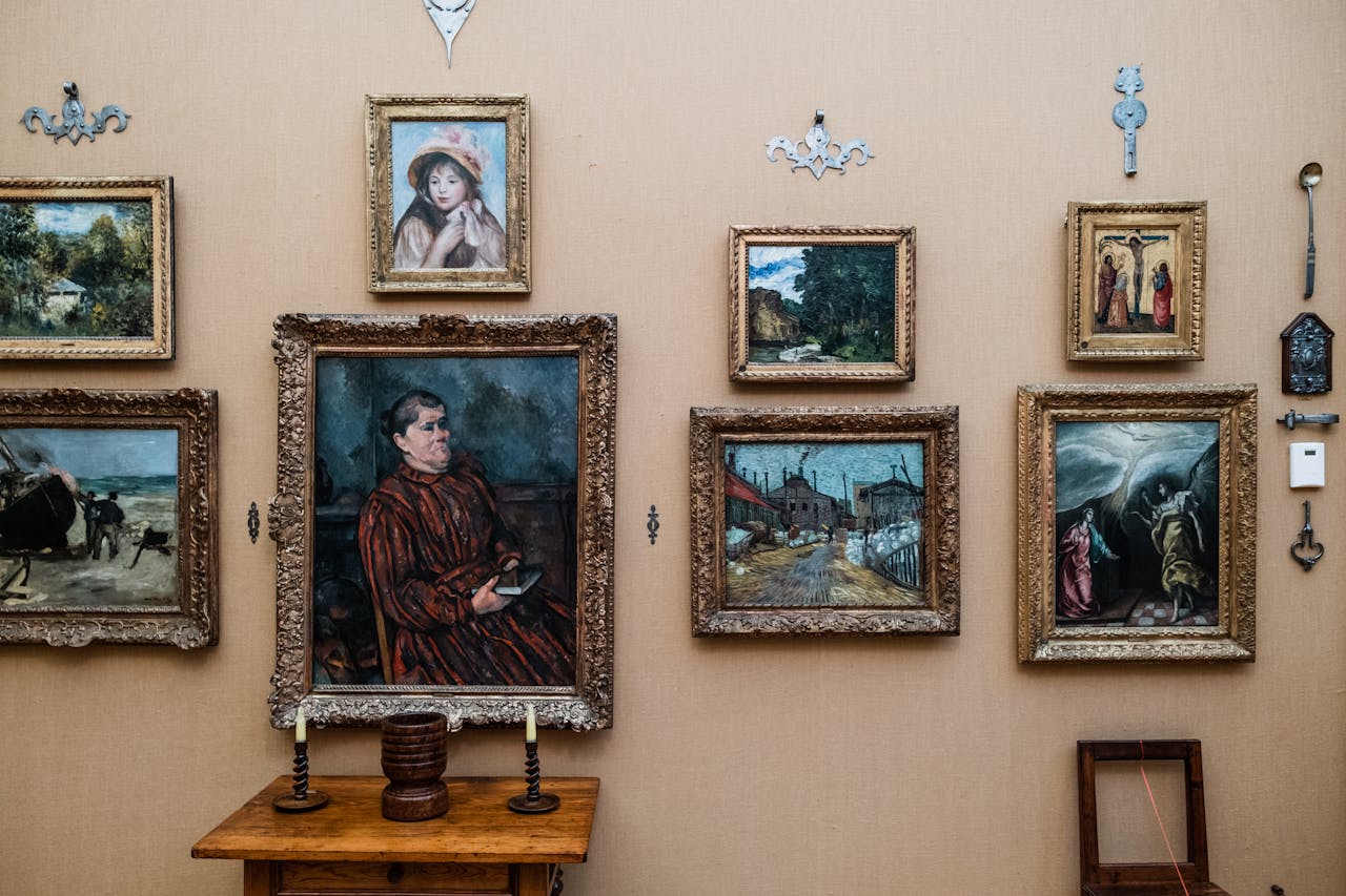 services-01 A gallery wall featuring a variety of framed paintings set against a beige background with decorative elements.