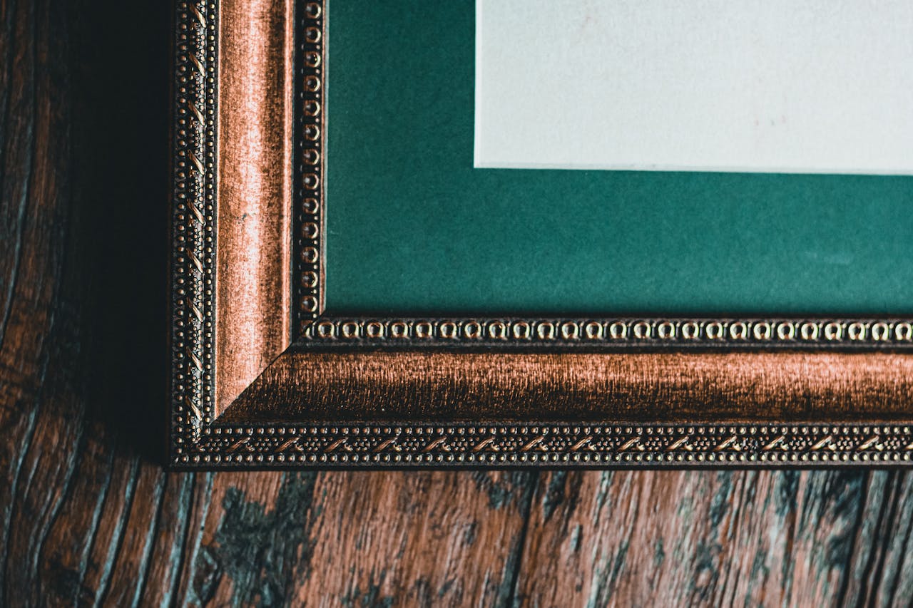 services-02 Close-up of an ornate vintage picture frame corner on textured wooden surface.