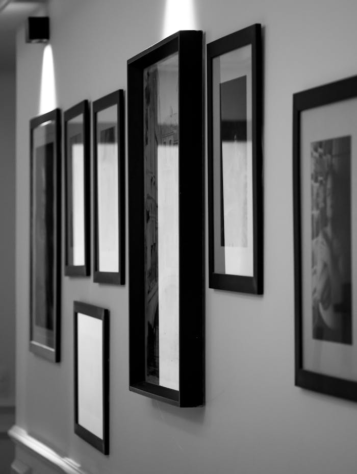 pexels photo 29985393 Monochrome wall display in an art gallery with framed pictures casting soft shadows.